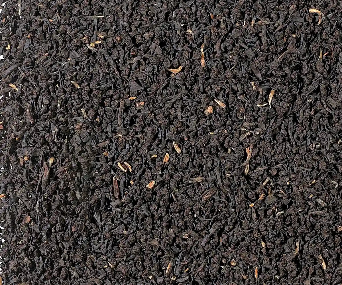 Irish Breakfast Schwarztee, fein gebrochene schwarze Teeblätter in Nahaufnahme, gleichmäßige dunkle Blattstruktur als Texturhintergrund