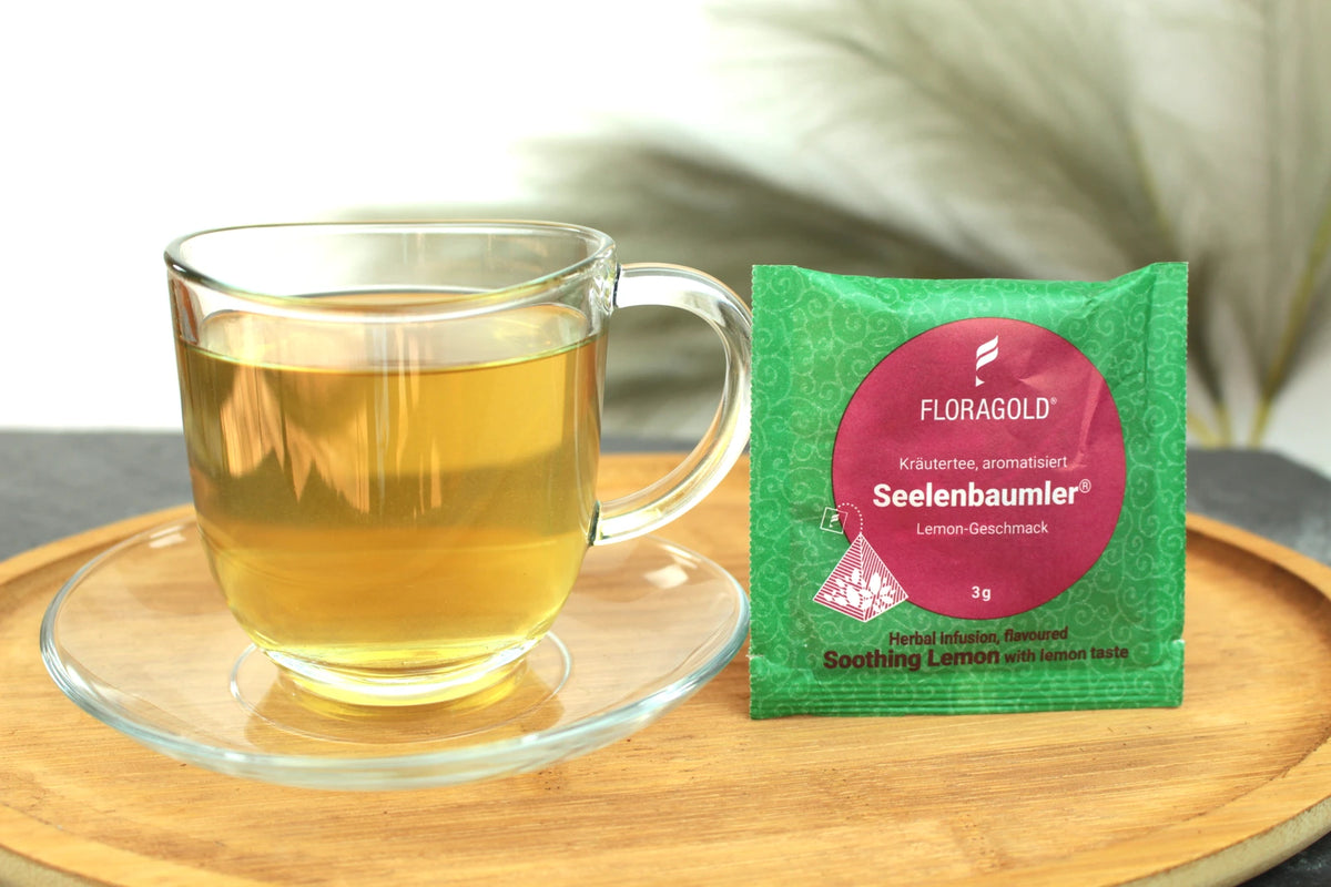 Produktfoto einer Tasse Tee und der Verpackung von Seelenbaumler, Entspannung pur mit Lemon-Geschmack.