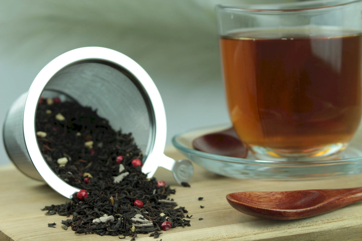Produktfoto einer Tasse Tee und der Verpackung von Süßes Marzipan, aromatische und verführerische Schwarzteemischung.