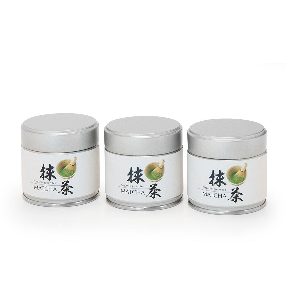 Drei silberne Dosen Bio Matcha Shizuoka mit japanischer Beschriftung auf weißem Hintergrund.