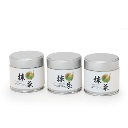 Drei silberne Dosen Bio Matcha Shizuoka mit japanischer Beschriftung auf weißem Hintergrund.