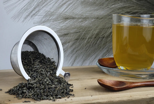 Grüner Tee Chun Mee in Teetasse, gelbgrüner Aufguss, loser Tee im Sieb