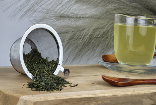 Gabalong Grüner Tee aus Japan, loser grüner Tee im Edelstahl-Teesieb, Teetasse mit hellgrünem Aufguss und Holzlöffel auf H
