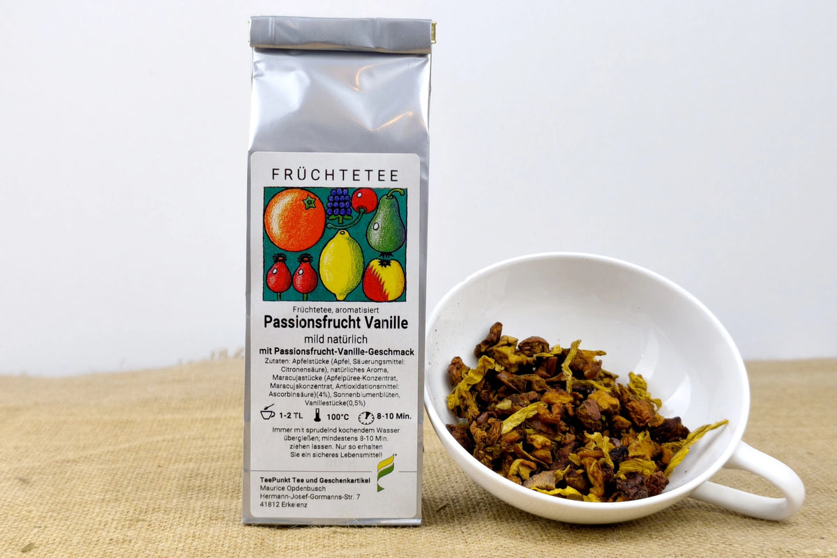 Silberne Packung Passionsfrucht Vanille Früchtetee neben einer weißen Tasse mit losem Früchtetee.