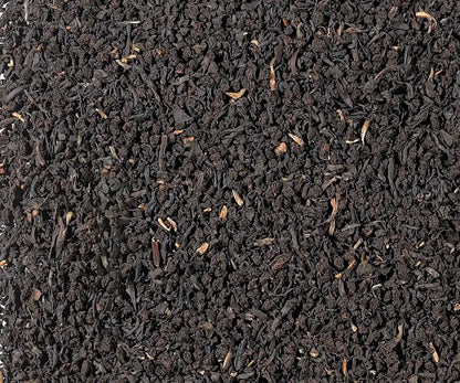 Irish Breakfast Schwarztee, fein gebrochene schwarze Teeblätter in Nahaufnahme, gleichmäßige dunkle Blattstruktur als Texturhintergrund