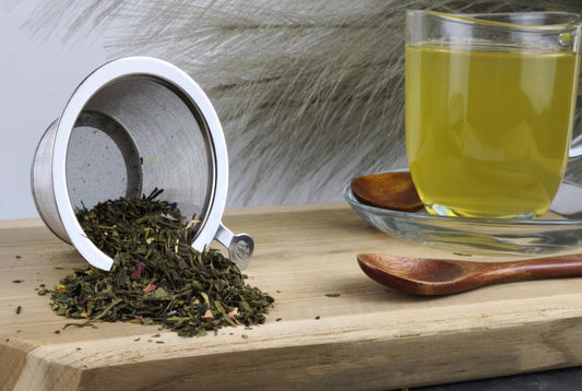 Grüner Tee Morgentau in Teetasse, hellgelber Aufguss, loser Tee im Sieb