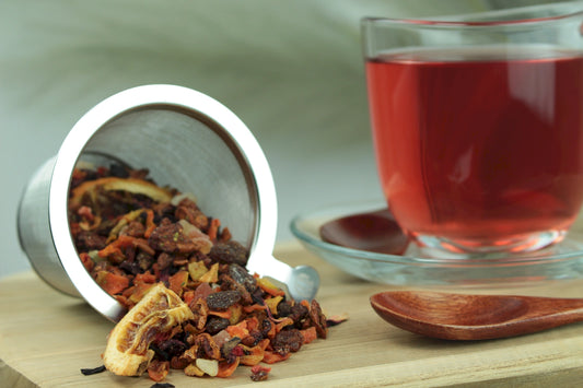 Produktfoto einer Tasse Tee und losen Teeblättern von Himmlische Früchte, aromatisierter Früchtetee mit Vitamin C und Erdbeer-Orange-Geschmack.