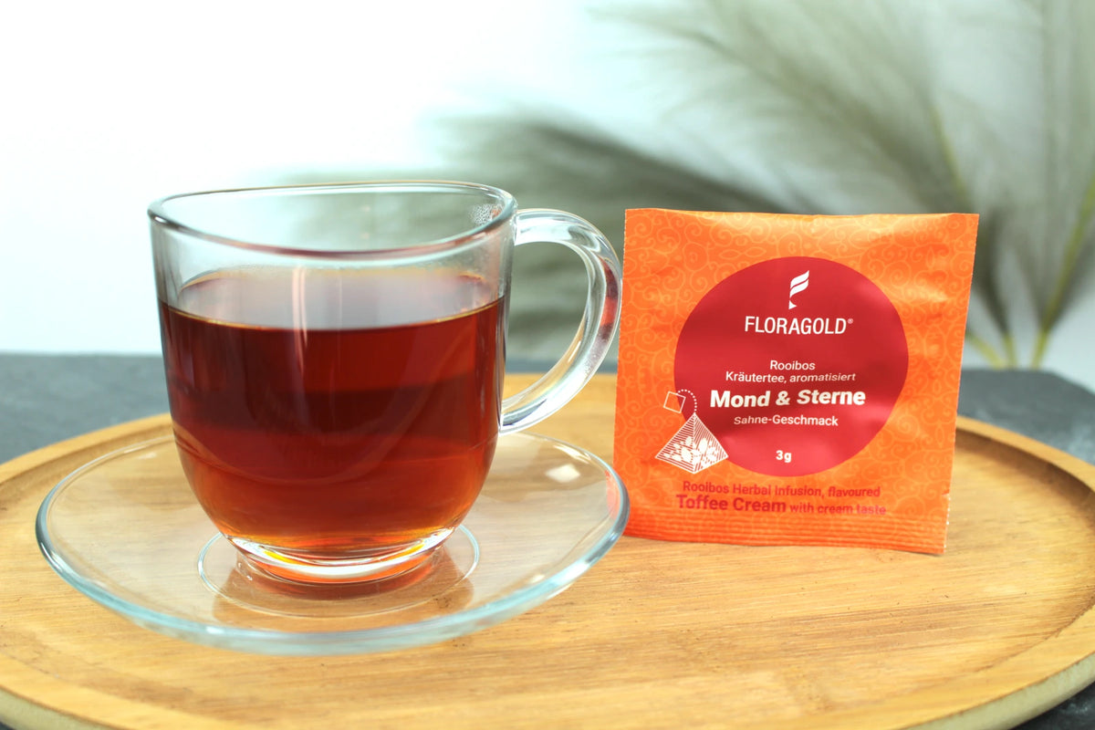 Produktfoto einer Tasse Tee und der Verpackung von Mond & Sterne, Rooibos mit zartem Sahne-Geschmack.