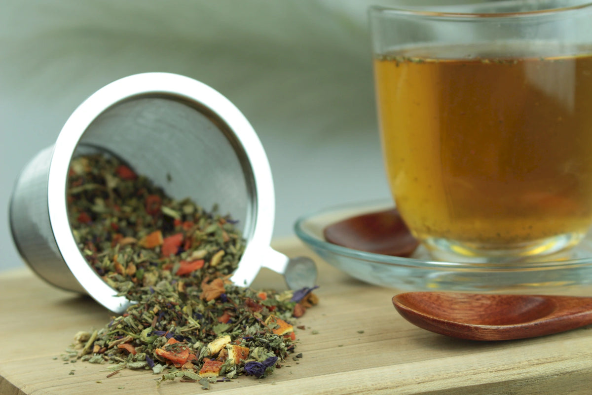 Produktfoto einer Tasse Tee und losen Teeblättern von Schweizer Kräutertee, aromatisierter Kräutertee mit Orange-Pfefferminz-Geschmack.