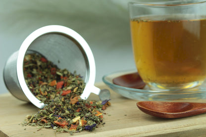 Produktfoto einer Tasse Tee und losen Teeblättern von Schweizer Kräutertee, aromatisierter Kräutertee mit Orange-Pfefferminz-Geschmack.