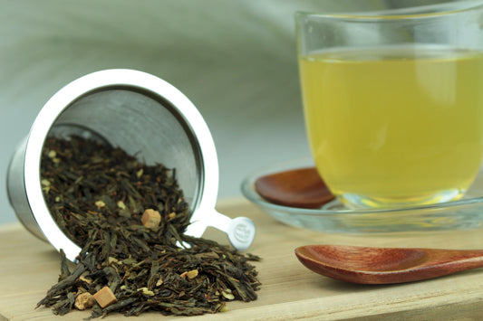 Produktfoto einer Tasse Tee und losen Teeblättern von Sencha Mandelmilch, aromatisierte Grünteemischung.