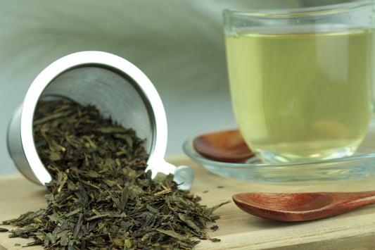 Produktfoto einer Tasse Tee und losen Teeblättern von Sencha Vanille, aromatisierter Grüntee.