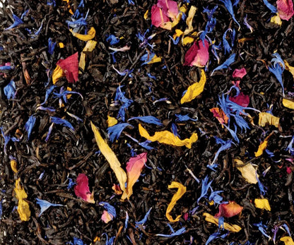 Freigestellte Nahaufnahme des aromatisierten Schwarztees "Südseezauber" mit Mango, Maracuja und Papaya, verziert mit blauen Kornblumenblüten und Rosenblütenblättern