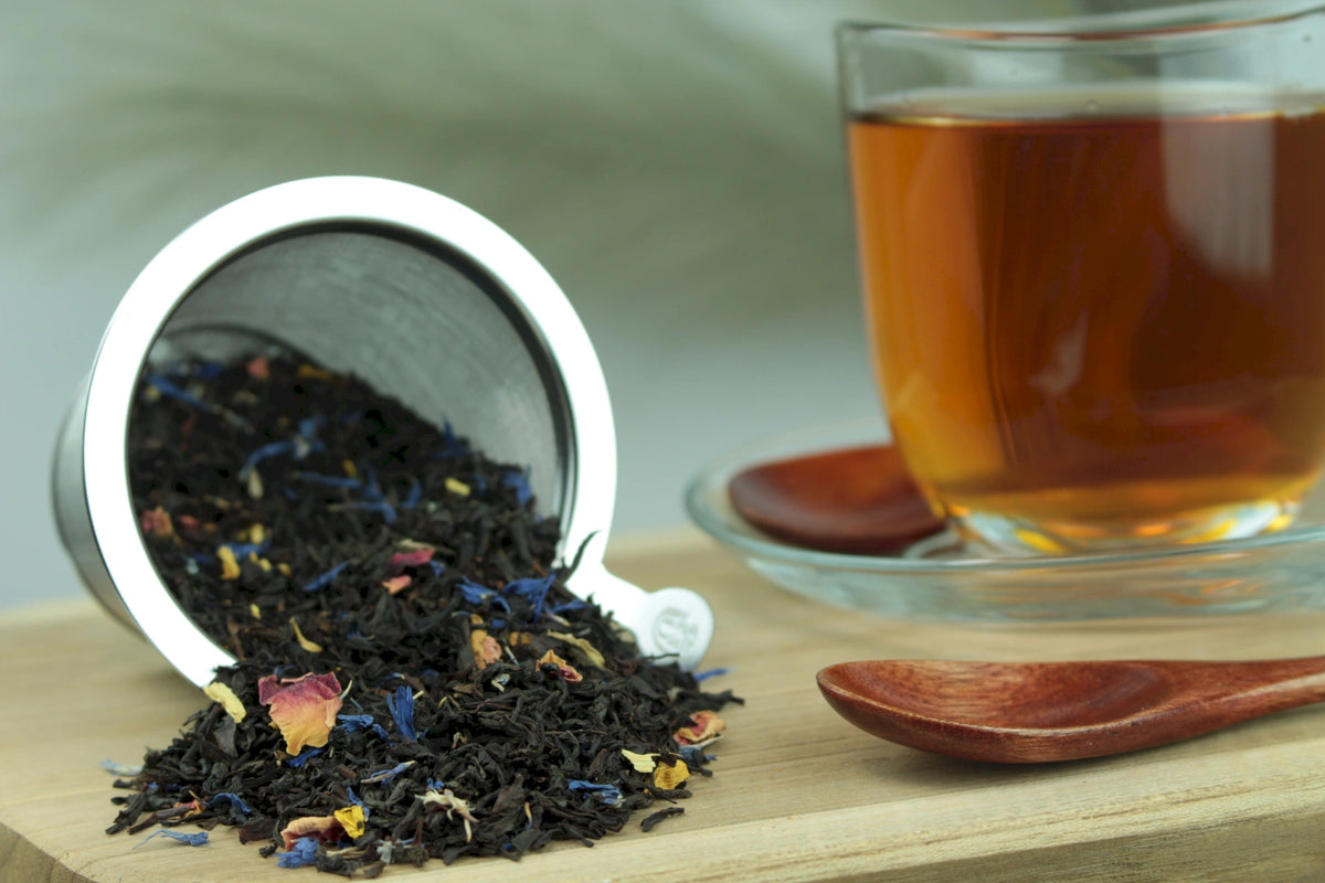 Produktfoto einer Tasse Tee und der Verpackung von Südseezauber, aromatisierter Schwarztee mit Mango, Maracuja und Papaya.