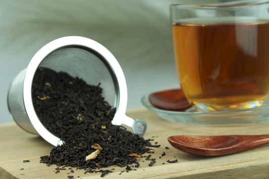 Produktfoto einer Tasse Tee und der Verpackung von Sweet Lemon mit Schalen, aromatisierter Schwarztee mit Litschi und Zitrone.
