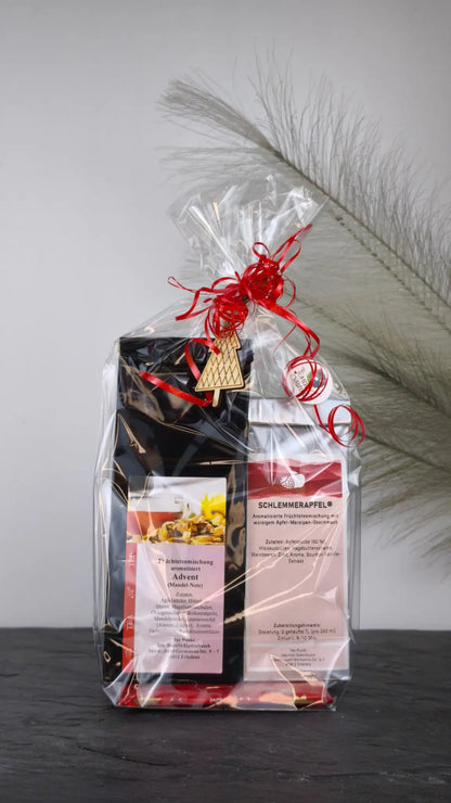 Advent Tee und Schlemmerapfel im Geschenkset, dekorativ verpackt mit Folie, rotem Geschenkband und weihnachtlichem Holzanhänger.
