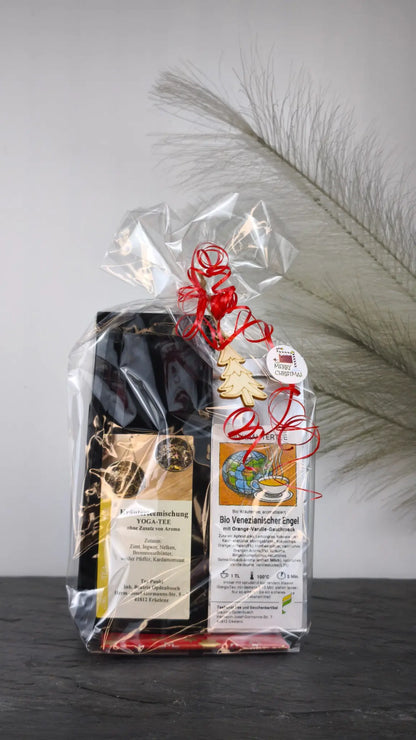 Tee Geschenkset mit Yoga-Tee und Bio Venezianischer Engel, liebevoll eingepackt in Folie mit roten Schleifen und Holzmotiv.
