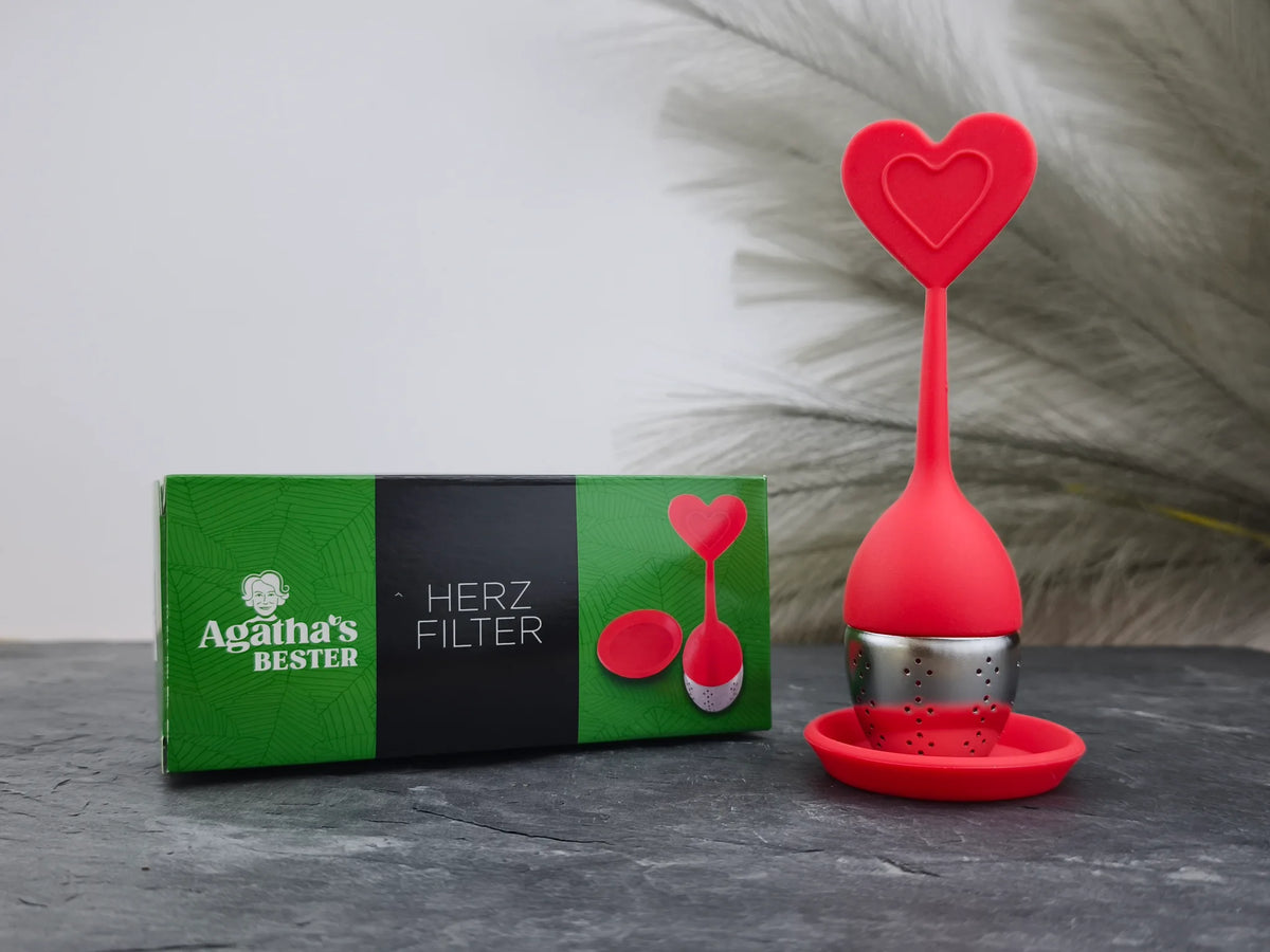 Produktfoto der Verpackung und des herzförmigen Teefilters „Herz“ von Agatha's Bester in Rot für eine stilvolle Teezubereitung mit Liebe.