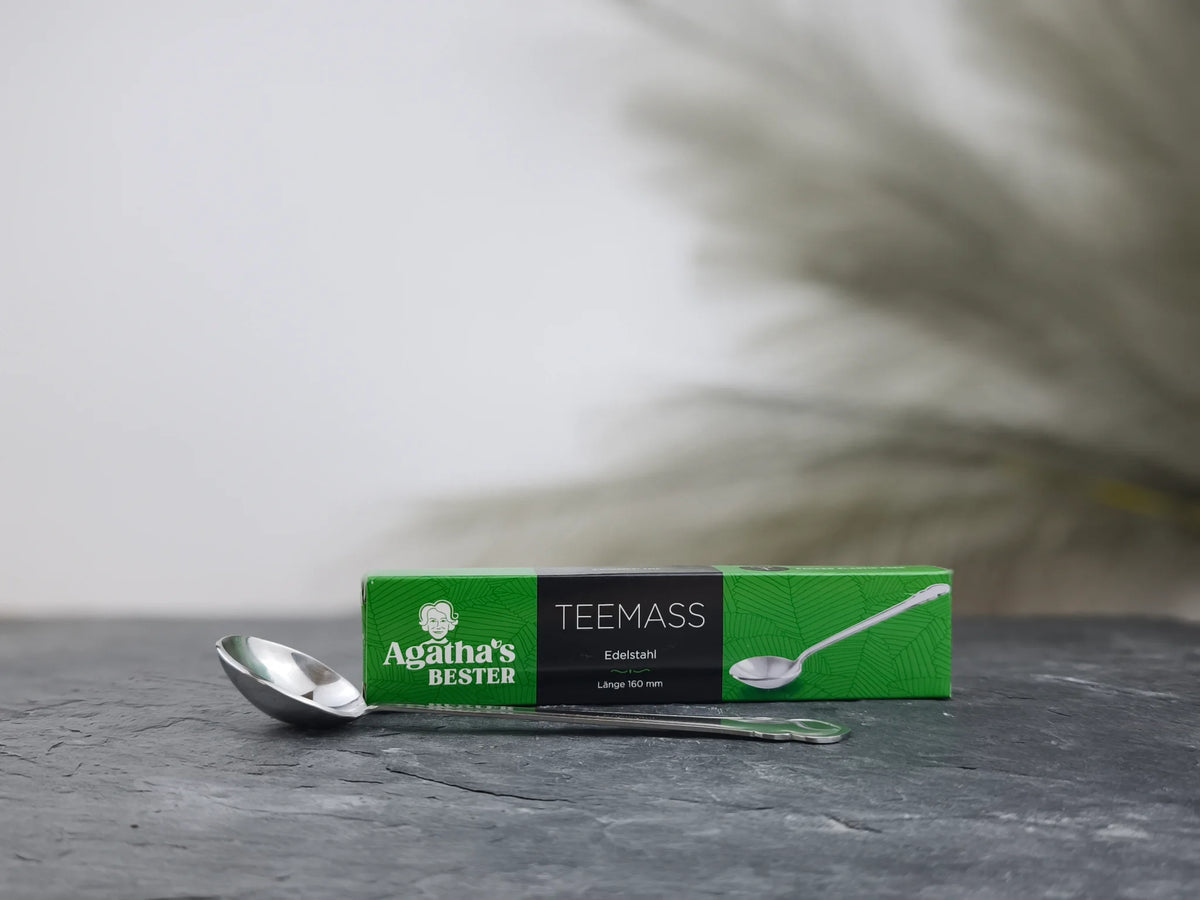 Produktfoto der Verpackung und des Teemaßes aus Edelstahl von Agatha's Bester für präzise Dosierung und perfekten Teegenuss.