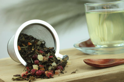 Produktfoto einer Tasse Tee und der Verpackung von Tempel der Götter, Premium Teemischung mit Lychee-Pfirsich-Geschmack.