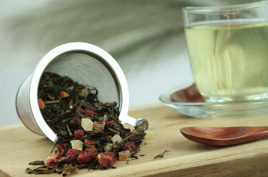 Produktfoto einer Tasse Tee und der Verpackung von Tempel der Götter, Premium Teemischung mit Lychee-Pfirsich-Geschmack.