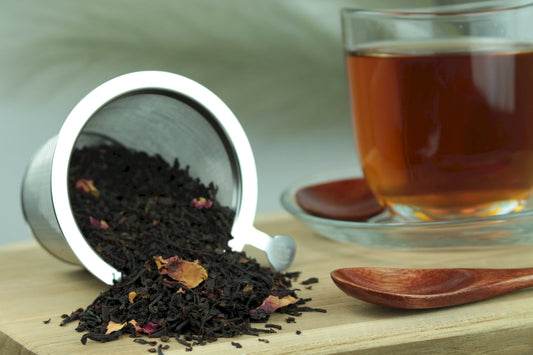 Produktfoto einer Tasse Tee und der Verpackung von Tropenfeuer, aromatisierter Schwarztee mit Jackfruit und Rosenblüten.