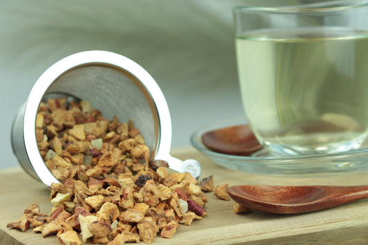Produktfoto einer Tasse Tee und losen Teeblättern von Türkischer Apfeltee, aromatisierte, säurearme Früchteteemischung mit Apfel und Ananas.