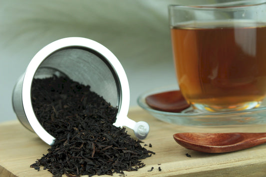 Produktfoto einer Tasse Tee und der Verpackung von Vanille, natürlich aromatisierter schwarzer Tee mit Bourbon-Vanille.