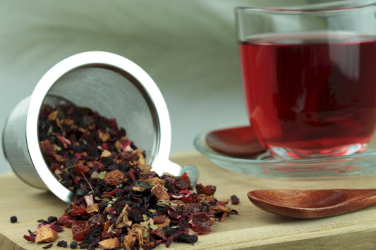 Produktfoto einer Tasse Tee und losen Teeblättern von Waldfrucht, aromatisierte Früchteteemischung mit Waldbeeren.