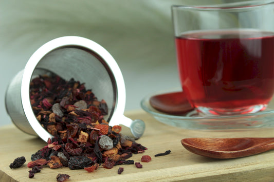 Produktfoto einer Tasse Tee und losen Teeblättern von Wildkirsche, aromatisierte Früchteteemischung mit intensivem Kirschgeschmack.