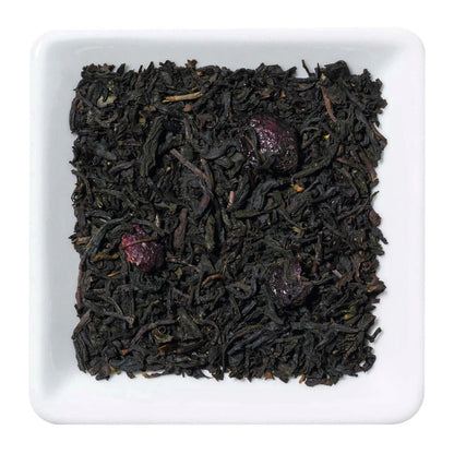 Freigestellte Nahaufnahme des aromatisierten Schwarztees "Wildkirsche" mit Waldbeeren und Kirschstücken.