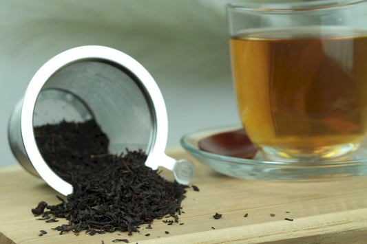 Produktfoto einer Tasse Tee und der Verpackung von Wildkirsche, aromatisierter Schwarztee mit Waldbeere und Kirsche.