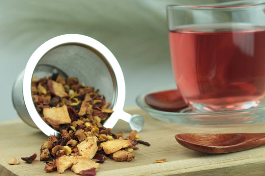 Produktfoto einer Tasse Tee und losen Teeblättern von Wildorange, natürlich aromatisierte Früchteteemischung mit Orange und Blüten.