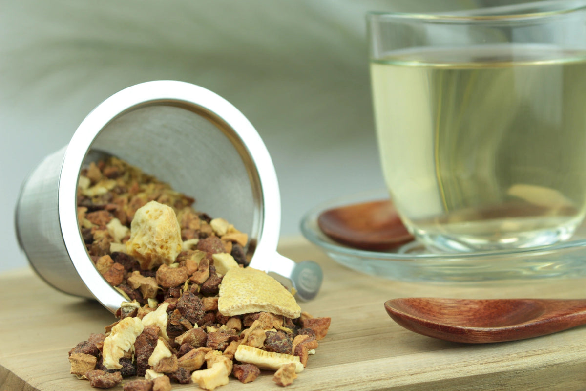 Produktfoto einer Tasse Tee und losen Teeblättern von Zitro-Schock, aromatisierte Früchteteemischung mit spritziger Zitrusnote und Physalis.